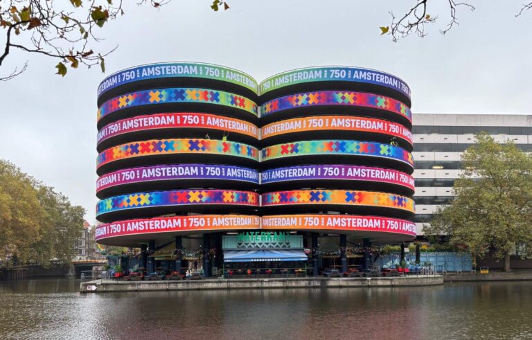 Spanduk raksasa setinggi 750 sentimeter terpasang di atas kafe Waterkant, mengubah garasi parkir di Marnixstraat menjadi pusat perhatian yang meriah (Sumber: https://amsterdam750.nl/)