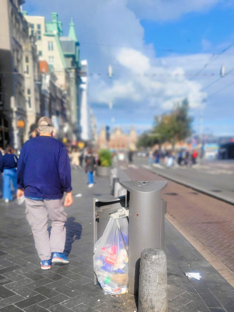 Pemandangan tempat sampah yang dibuka paksa oleh pemulung dengan latar belakang Stasiun Sentral Amsterdam dan jalan Damrak, daerah turis yang sibuk (Foto: Hengky Kurniawan)