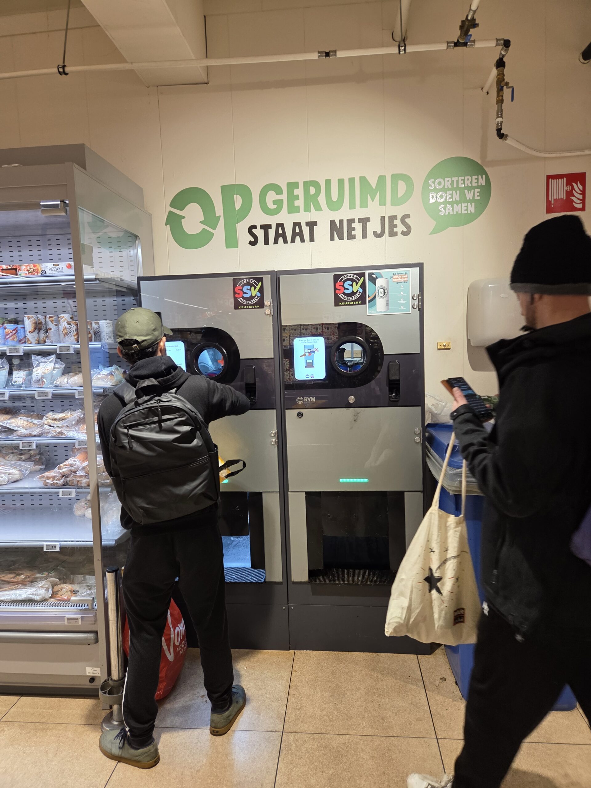 Tampak dua orang pengunjung mengklaim deposito di mesin setor botol otomatis yang disediakan oleh supermarket di Belanda (Foto: Hengky Kurniawan)